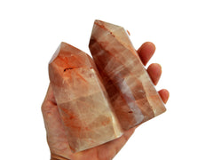 Two chunky fire quartz tower crystals on hand with white background