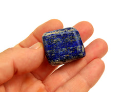 One blue lapis lazuli tumbled stone 30mm on hand with white background