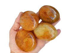 Four yellow hematoid quartz palmstones 50mm-65mm on hand with white background