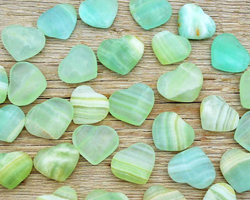 Several small pistachio calcite hearts 35mm-40mm on wood table