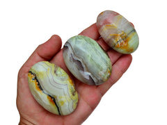 Three pink banded onyx palm stones 60mm-70mm on hand with white background
