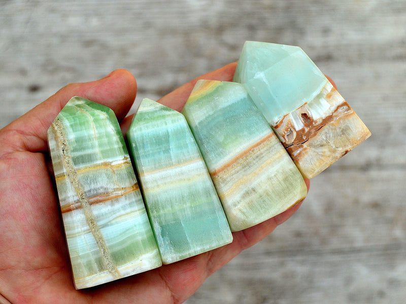 Four banded pistachio calcite towers 55mm - 60mm on hand with wood background