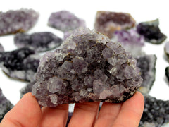 One amethyst druzy 90mm on hand with background with some crystals on white
