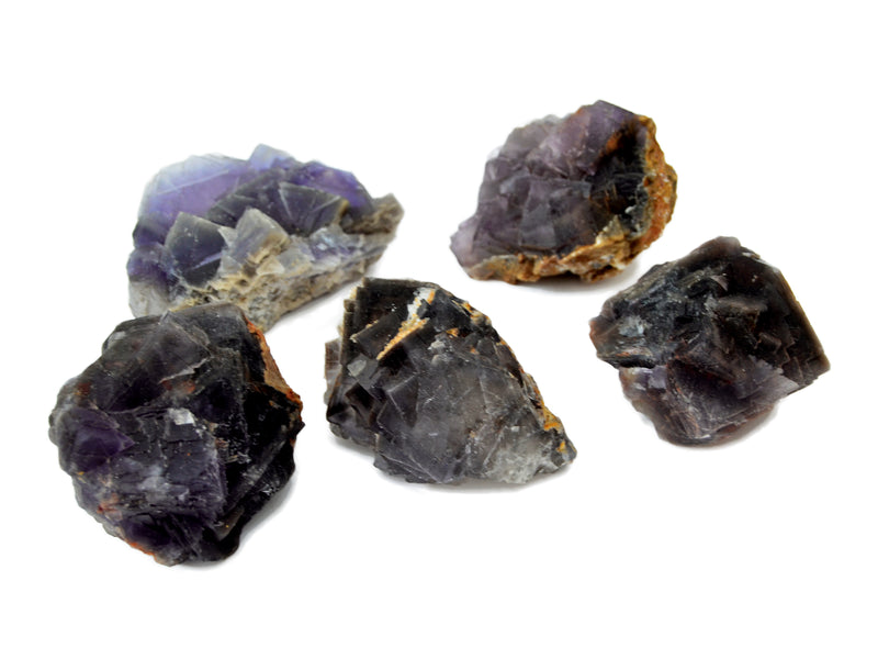 Five purple fluorite raw crystals on white background