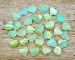 Several small green pistachio calcite crystal hearts 35mm-40mm on wood table
