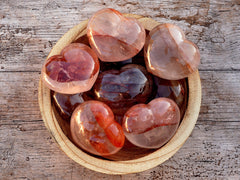 Some fire quartz heart stones 67mm inside a wood bowl on wood table