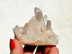 Natural rough crystal quartz cluster on hand with white background