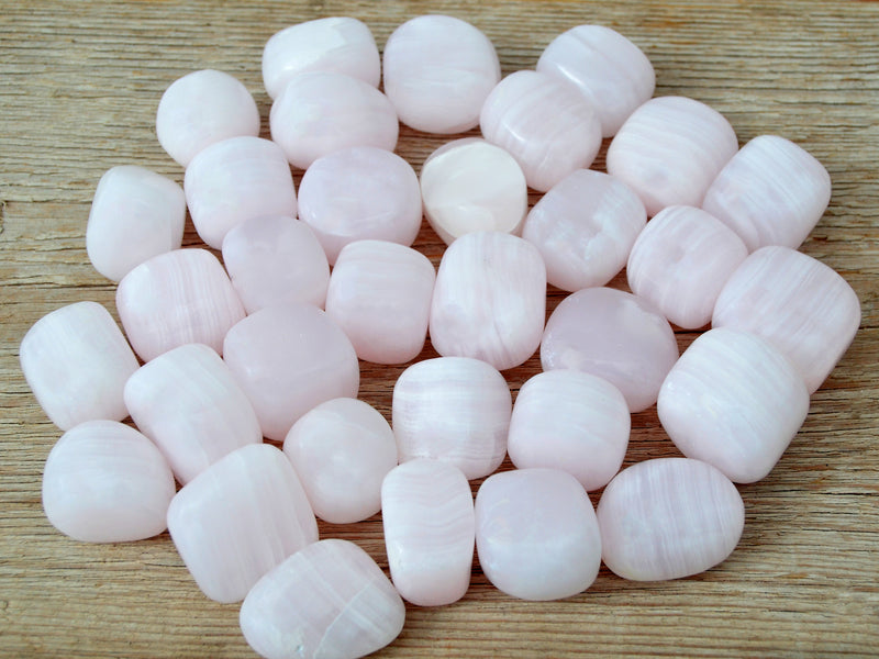 Several pink mangano calcite mini tumbled crystals 20mm-30mm on wood table