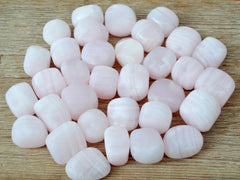 Several pink mangano calcite mini tumbled crystals 20mm-30mm on wood table