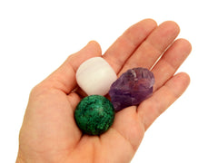 One small tumbled mangano calcite, raw amethyst and chrycolla sphere 30mm on hand with white background 