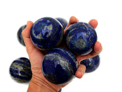 Three lapis lazuli sphere stones 60mm-65mm on hand with background with some crystals on white