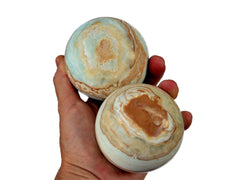 Two caribbean calcite crystal balls 70mm-75mm on hand with white background