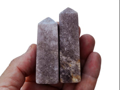 Two purple lepidolite obelisk crystals 65mm-70mm on hand with white backround