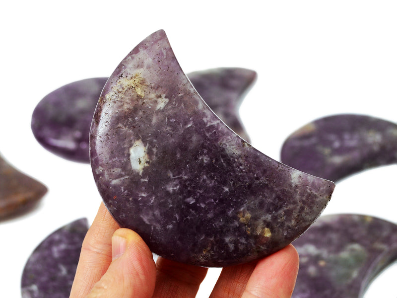 One purple lepidolite moon 90mm on hand with background with some specimens on white