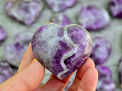 One chevron amethyst heart 50mm on hand with background with some hearts on wood table
