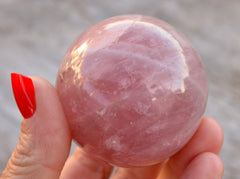 Large rose quartz sphere stone 60mm on hand with wood background
