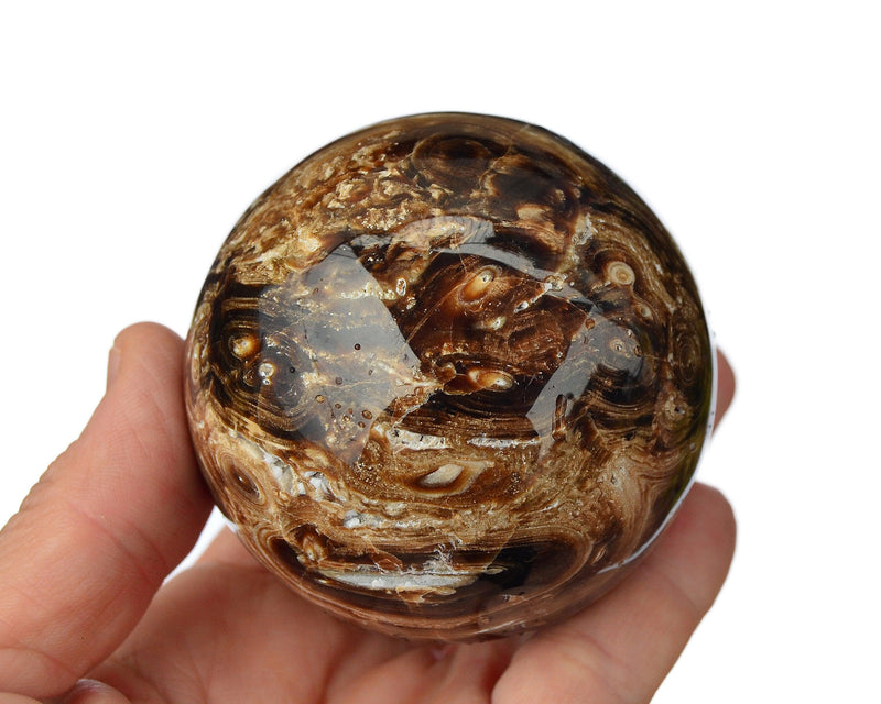 One chocolate calcite sphere crystal 70mm on hand with white background