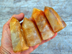 Fpur chunky golden healer quartz towers on hand with wood background