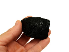 One raw black tourmaline tumbled crystal 50mm on hand with white background