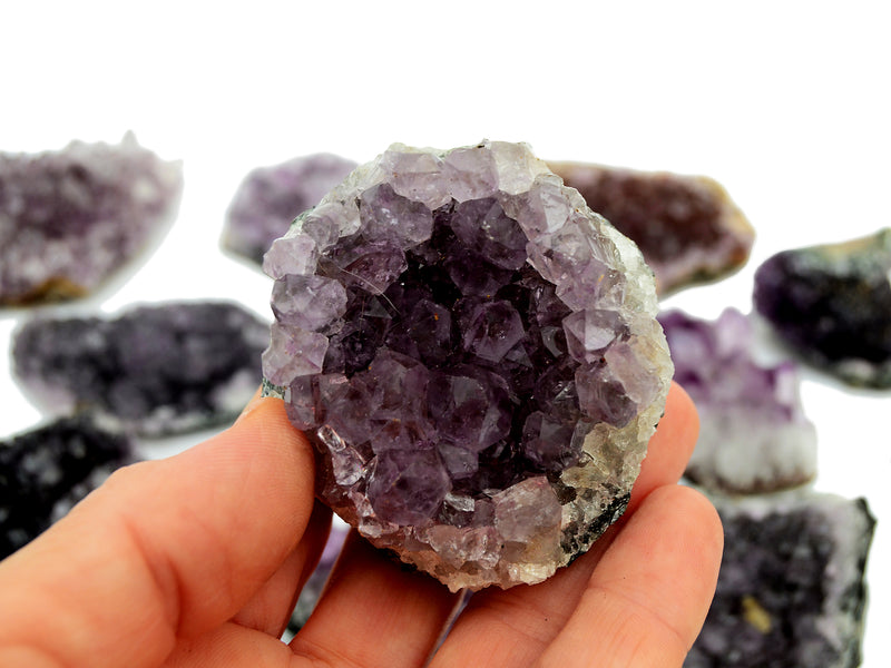 One natural amethyst druzy stone 80mm on hand with background with some clusters on white
