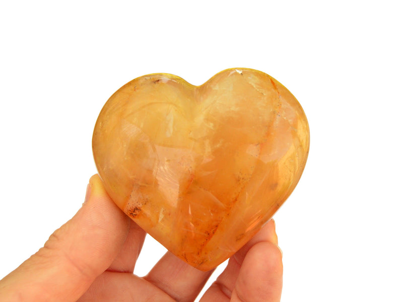 One golden healer quartz heart crystal 60mm on hand with white background