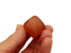 One honey calcite tumbled stone 30mm on hand with white background