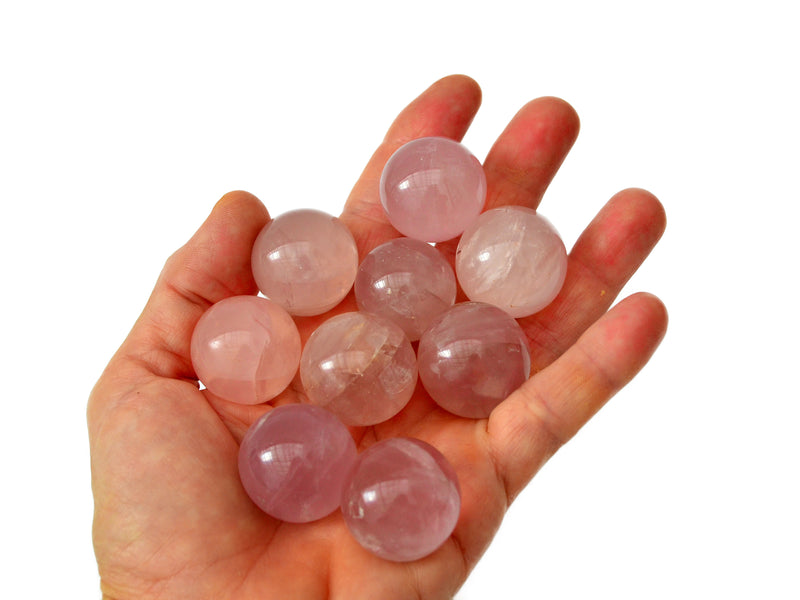 Some pink quartz small spheres 25mm-35mm on hand with white background