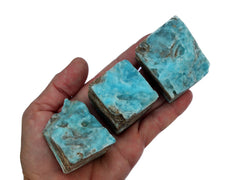 Three small blue aragonite raw stones on hand with white background 