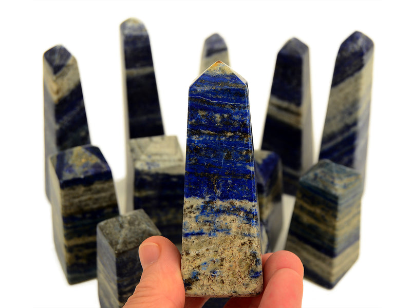A lapis lazuli crystal on hand with other crystals in the background