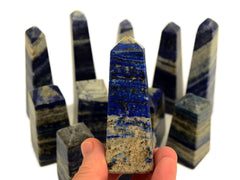 A lapis lazuli crystal on hand with other crystals in the background