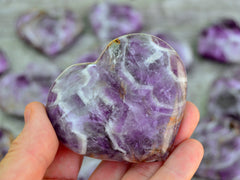 One chevron amethyst heart 60mm on hand with background with some hearts on wood table