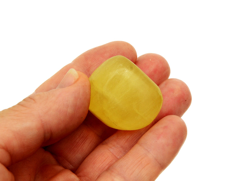 One yellow calcite tumbled crystal 30mm on hand with white background