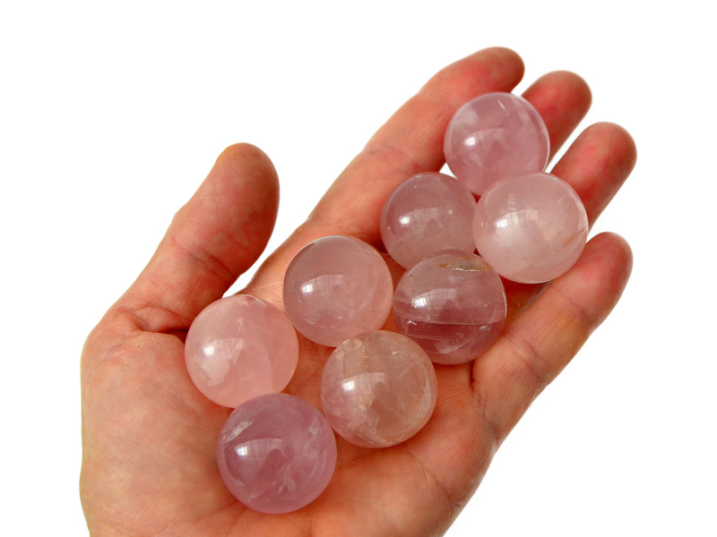 Some rose quartz small crystal spheres 25mm on hand with white background