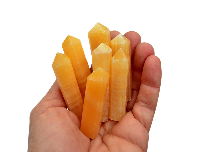 Some small orange calcite point crystals 50mm-60mm on hand with white background