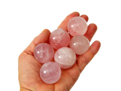 Some rose quartz crystal spheres 30mm-35mm on hand with white background