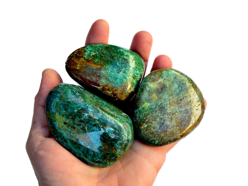Three large green chrysocolla tumbled crystals on hand with white background