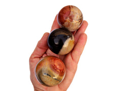 Three multicolor desert jasper sphere crystals 45mm - 50mm on hand with white background
