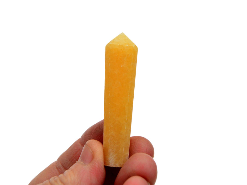 One small orange calcite crystal tower 60mm on hand with white background