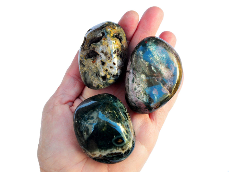 Three large sea jasper tumbled stones on hand with white background