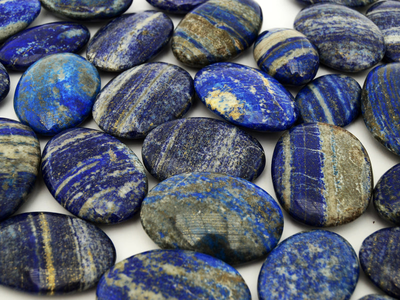 Several lapis lazuli oval palmstones 55mm-75mm on white background
