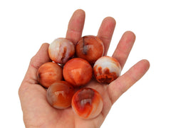 Some small carnelian crystal balls on hand with white background