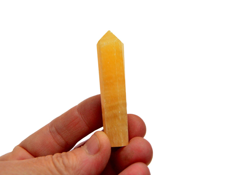 One small orange calcite faceted crystal point  50mm on hand with white background