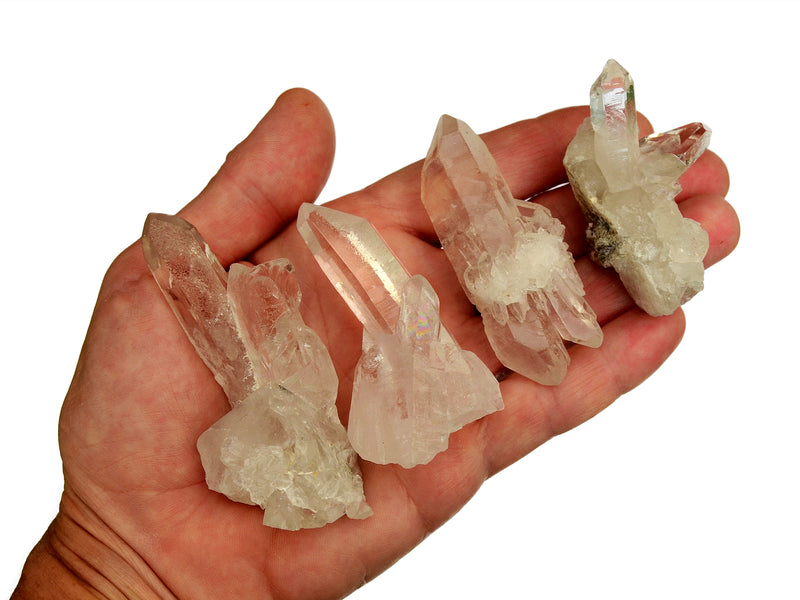 Four small clear quartz clusters 40mm-50mm on hand with white background