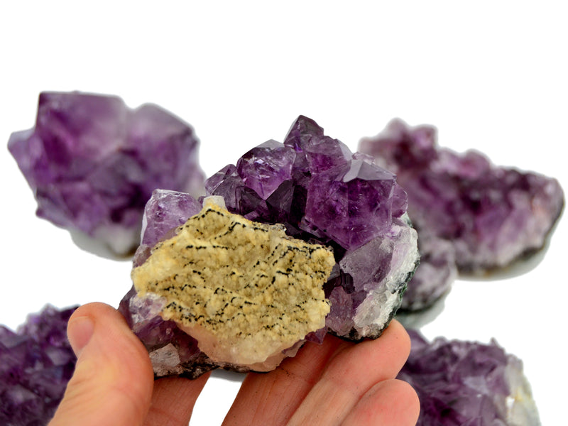 One brazilian druzy amethyst with calcite inclusion on hand with background with some crystaks on white