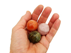 Orange carnelian, rose quartz and chrysocolla spheres 30mm on hand with white background