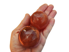 Two natural honey calcite ball stones 45mm-55mm on hand with white background