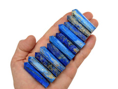 Eleven blue lapis lazuli faceted crystals points 40mm-50mm on hand with white background