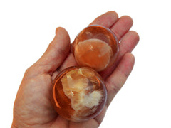 Two natural honey calcite crystal balls 45mm-55mm on hand with white background