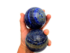 Two large lapis lazuli spheres 65mm-70mm on hand with white background