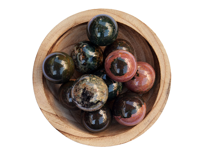 Several multicolor sea jasper sphere crystals 45mm-55mm inside a wood bowl on white background